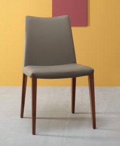 Flory est une chaise en frêne au design linéaire réalisée en Italie. Cette chaise de salle à manger haut de gamme est disponible en eco-cuir ou velours.