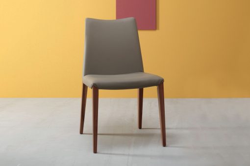 Flory est une chaise en frêne au design linéaire réalisée en Italie. Cette chaise de salle à manger haut de gamme est disponible en eco-cuir ou velours.