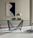 A luxurious table with barrel glass top and metal sinuous base. Andrea Lucatello created it to furnish the most elegant homes. Free home delivery.