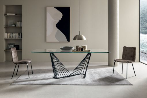 A luxurious table with barrel glass top and metal sinuous base. Andrea Lucatello created it to furnish the most elegant homes. Free home delivery.