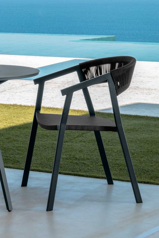 Ken è una sedia da esterno con braccioli con struttura in alluminio seduta in textilene schienale rivestito in corda sintetica. Colori grigio carbone e nero