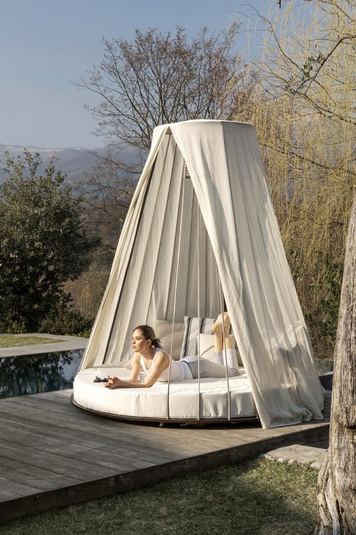 Majestueux et luxueux daybed de jardin. Matelas rond, structure en acier et bois, cordes nautiques et légers rideaux. Suspension lumineuse intégrée.