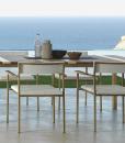 Garden table with stainless steel frame. Top in iroko wood and travertine. Patio furniture design by Ramon Esteve. Shop online for outdoor table and chairs.