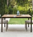 Garden table with stainless steel frame. Top in iroko wood and travertine. Patio furniture design by Ramon Esteve. Shop online for outdoor table and chairs.