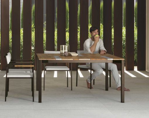 Garden table with stainless steel frame. Top in iroko wood and travertine. Patio furniture design by Ramon Esteve. Shop online for outdoor table and chairs.