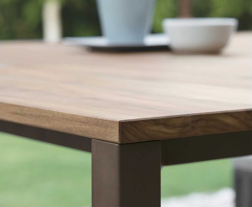 Garden table with stainless steel frame. Top in iroko wood and travertine. Patio furniture design by Ramon Esteve. Shop online for outdoor table and chairs.